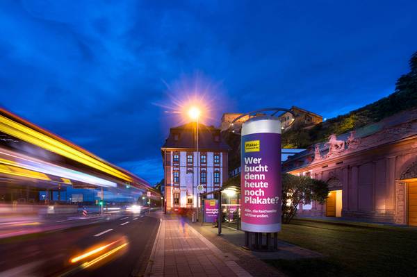 Werbesäule an Bushaltestelle mit Motiv "Wer bucht denn heute noch Plakate"